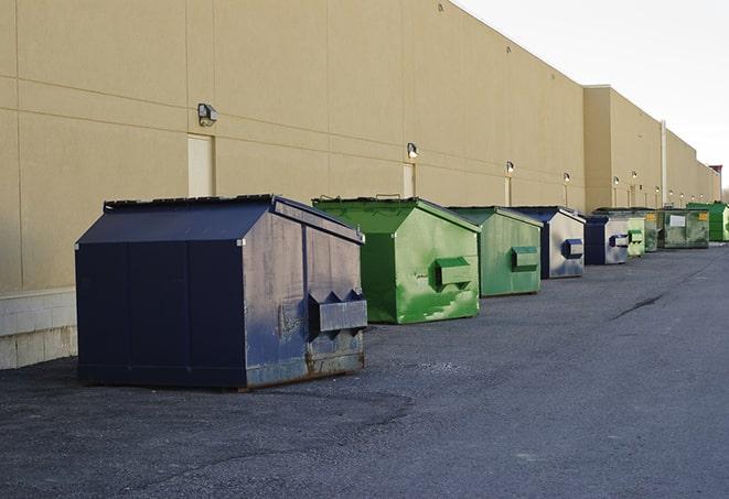 a construction worker empties a wheelbarrow of waste into the dumpster in Broadway